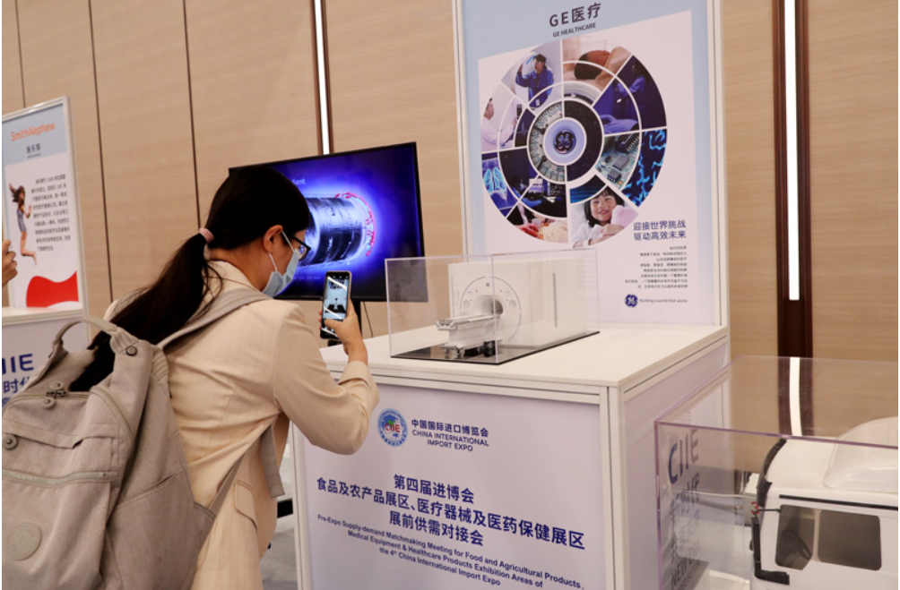 第四届进博会食品及农产品展区、医疗器械及医药保健展区展前供需对接会的参会嘉宾用手机拍摄参展企业的展品模型